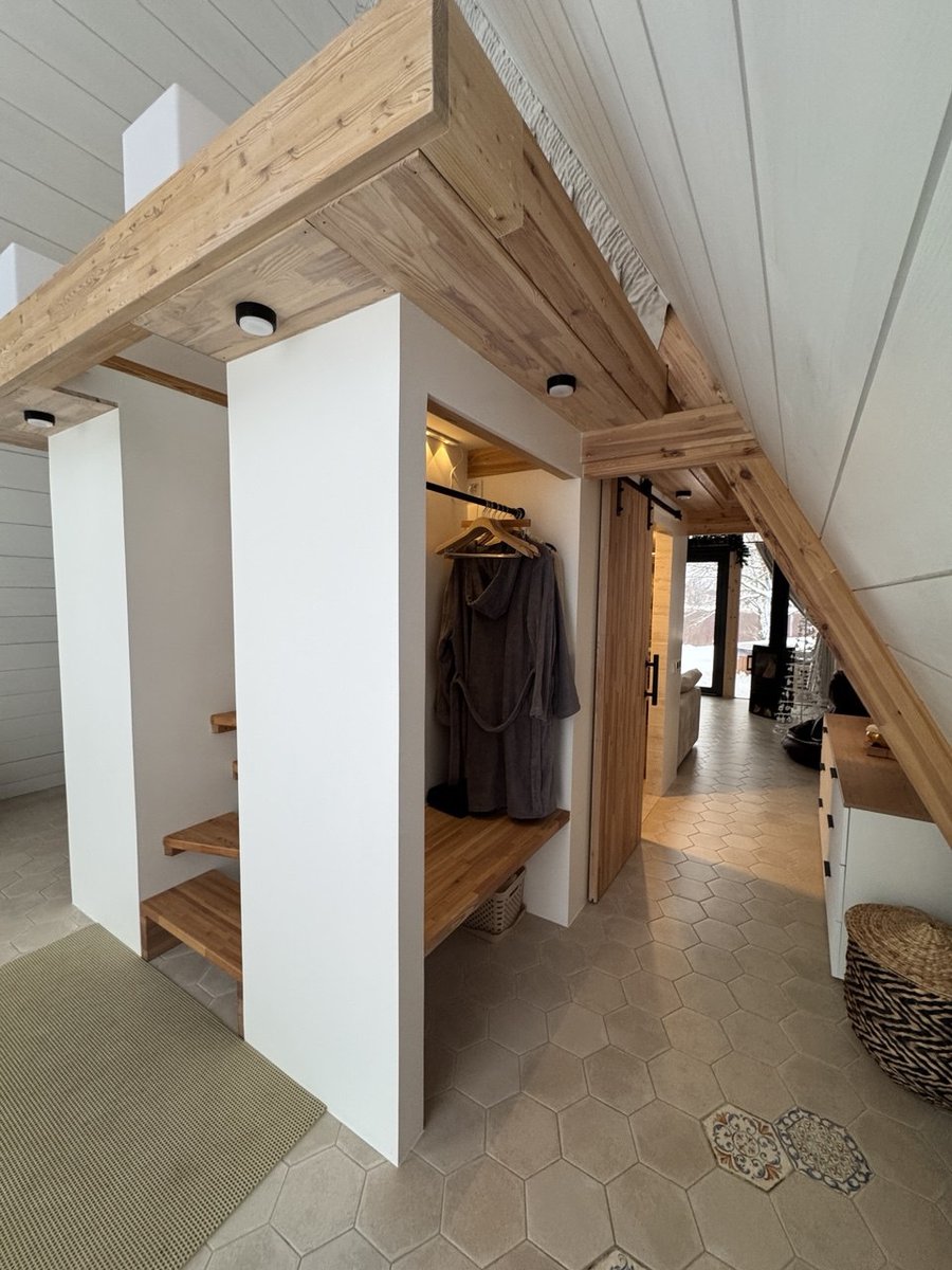 Зона гардероба в A-frame: деревянная раздвижная дверь, вешалка с халатом, гексагональная плитка